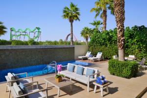 a patio with chairs and a swimming pool with palm trees at Lapita, Dubai Parks and Resorts, Autograph Collection in Dubai