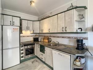 a kitchen with white cabinets and a white refrigerator at Apartamento Manilva con terraza y piscina in Manilva