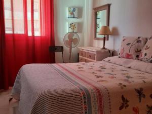 een slaapkamer met een bed, rode gordijnen en een spiegel bij Apartamento Manilva con terraza y piscina in Manilva +17 foto's