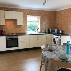 a kitchen with white cabinets and a table with chairs at The Annexe - Spacious 2 bedroom detached cottage in Cardigan