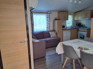 a kitchen and a living room with a couch and a table at GH Vacances La Réserve in Gastes