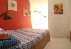 a bedroom with a bed with an orange wall at Odoya Guest House in Salvador