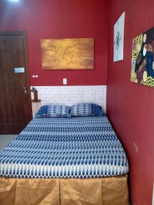 um quarto com uma cama numa parede vermelha em Odoya Guest House em Salvador