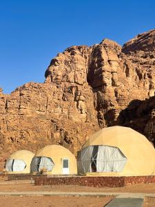 two domes in front of a rocky mountain at Wadi Rum stargazing camp in Wadi Rum