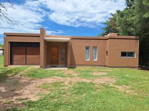 a brown house with a large yard at Casa Frente Dique Piedras Moras in Almafuerte