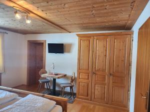 a bedroom with a bed and a table and a cabinet at Pension Wötzinghof in Kirchberg in Tirol