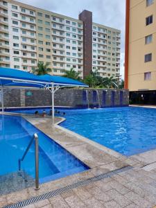 a swimming pool with a blue umbrella and some buildings at Cobertura Parque das Aguas in Caldas Novas