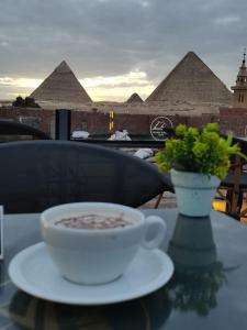 a cup of soup on a table with pyramids in the background at Loca Pyramids View in Cairo