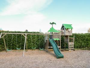 a playground with a slide and a swing set at Railway Station Cottage in Llandrindod Wells