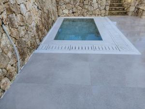 a pool of water with a stone wall and stairs at Luxury Villa Breeze with Private Pools in Dassia
