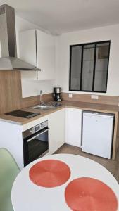 uma cozinha com uma mesa, um fogão e um lavatório em Nid douillet en Suisse Normande em Thury-Harcourt