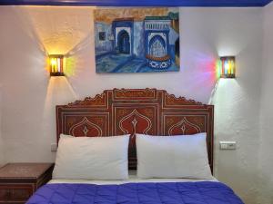 a bed with two pillows and a painting on the wall at Blue city Chefchaouen in Chefchaouene