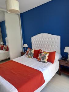 um quarto azul com uma cama branca com almofadas vermelhas em Departamento Playa 3 em Mar del Plata