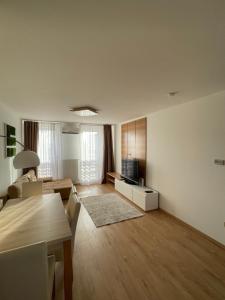 een grote woonkamer met een tafel en een televisie bij Sarló Apartman in Debrecen