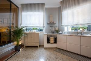 a large kitchen with white cabinets and windows at TRENTINO LODGE Piazza Municipio in Strigno