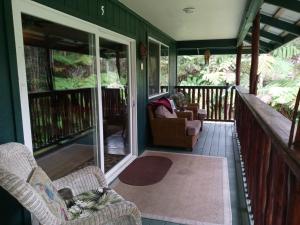 a screened in porch with chairs and a couch at Aloha Crater Lodge in Volcano