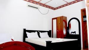 1 dormitorio con 1 cama y 1 silla roja en New AT hotel, en Jaffna