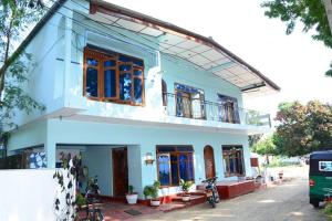 ein blaues Haus mit Fenstern und Motorrädern davor in der Unterkunft New AT hotel in Jaffna