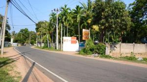 una calle vacía con palmeras y una valla en New AT hotel en Jaffna