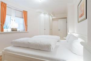 a white bedroom with a white bed and a window at Haus-Meerblick in Rantum