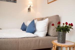 eine Couch mit Kissen und eine Vase mit roten Blumen in der Unterkunft Haus Ankerlicht 1.OG Wohnung 66 in Westerland