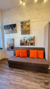 um sofá castanho com almofadas laranja num quarto em Квартира-студія в самому центрі міста біля Кобилянської em Chernivtsi