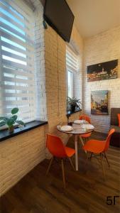 een woonkamer met een tafel en oranje stoelen bij Квартира-студія в самому центрі міста біля Кобилянської in Tsjernivsi