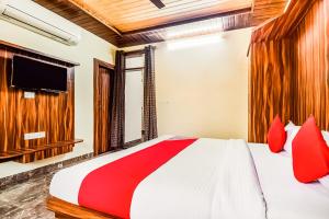 1 dormitorio con 1 cama con almohadas rojas y TV en Eleven Suites en Kota