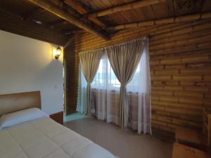 1 dormitorio con 1 cama y una ventana con cortinas en De Bambú Guatavita, en Guatavita