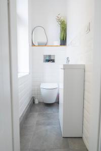 biała łazienka z toaletą i umywalką w obiekcie Torun Bridge Apartament w Toruniu