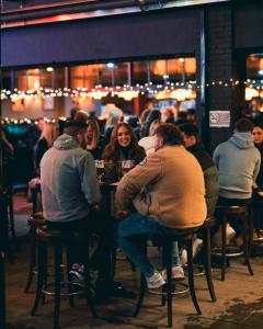 un grupo de personas sentadas en una mesa en un bar en Mary Mullen's Rooms Eyre Square. en Galway