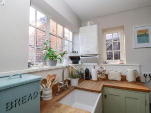 a kitchen with white cabinets and a wooden counter top at Rosemary Cottage, Aldeburgh in Aldeburgh