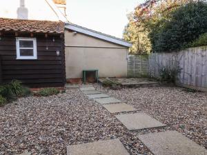 un patio trasero con un camino de piedra junto a una casa en 2 Greensleeves en Saxmundham