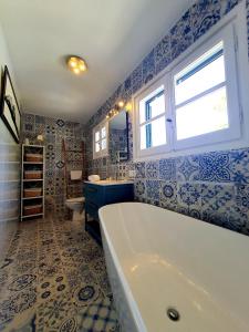 baño azul y blanco con bañera y ventana en Galdana's House, en Cala Galdana
