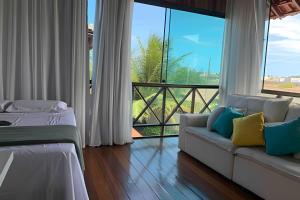 a living room with a couch and a large window at Village Praia dos Carneiros 3 com 6 quartos e Hidro in Tamandaré