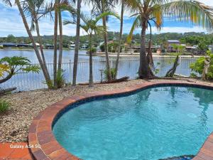 a swimming pool with palm trees and a body of water at Isle of Palms 112 in Gold Coast