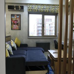 a living room with a blue couch and a window at Iris Apartments B in Tashkent