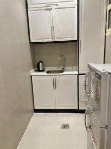 una piccola cucina con lavandino e armadietti bianchi di 106 A شقة جميلة بغرفتين نوم ودخول ذاتي a Riyad