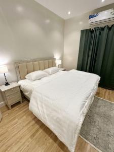 106 A شقة جميلة بغرفتين نوم ودخول ذاتي في الرياض: غرفة نوم بسرير ابيض كبير وستارة خضراء