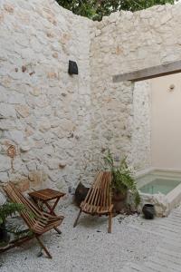 two chairs and a table next to a stone wall at Hermosa casa junto a la muralla in Campeche