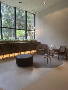 uma sala de estar com cadeiras, uma mesa e um banco em Studio Moderno em Pinheiros - 300m do Metrô e HC em São Paulo