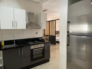 a kitchen with white cabinets and a stainless steel refrigerator at Studio in Kamal Park Center Mohemadia in Mohammedia