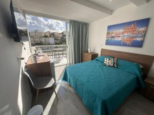 a bedroom with a green bed and a large window at La Bella Guesthouse in St. Julianʼs