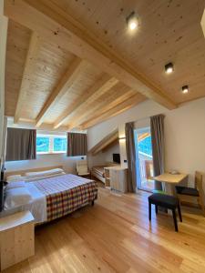 una camera con un grande letto e soffitti in legno di Hotel Garni Civetta a Selva di Cadore