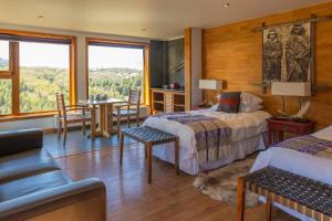 1 dormitorio con 2 camas y comedor con mesa en HOTEL NOMADES PATAGONIA, en Coyhaique