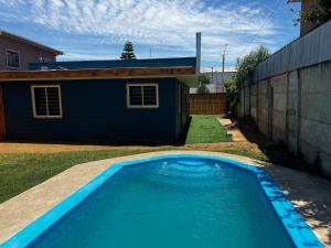 a blue swimming pool in front of a house at Alojamiento Rustico Belloto (2) in Quilpué