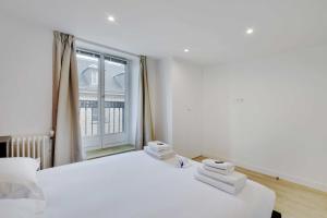 a bedroom with two beds and a large window at CMG - Residence OpéraGrands Magasins in Paris