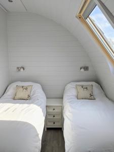 2 Betten in einem kleinen Zimmer mit Fenster in der Unterkunft Wolds Wine Estate 