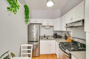 uma cozinha com armários brancos e um frigorífico de aço inoxidável em Cozy Somerville Studio 2 Mi to Boston, Walk to T! em Somerville