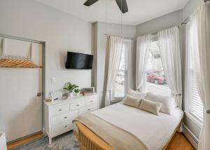 1 dormitorio con 1 cama, TV y ventanas en Cozy Somerville Studio 2 Mi to Boston, Walk to T!, en Somerville